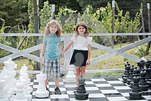 Brother and sister playing on big chess board. Little boy and girl kids enjoying spring. Kids walking at backyard. Best