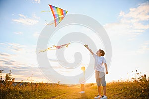 Brother and sister playing with kite and plane at the field on the sunset.