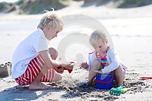 Brother and sister playing with sand on the beach