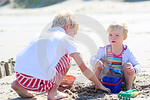 Brother and sister playing with sand on the beach