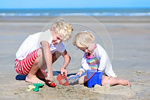 Brother and sister playing with sand on the beach