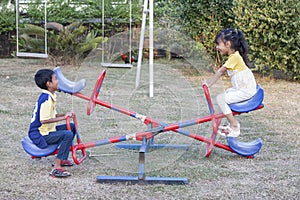 Brother and Sister playing seesaw in the playground. photo