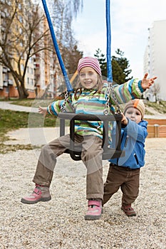 Brother and sister playing on the swing