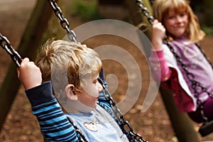 Brother and Sister playing on swings
