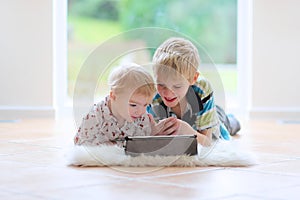 Brother and sister playing with tablet pc indoors