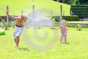 Brother and sister playing with water hose in the garden