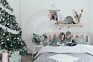 Brother and sister read an interesting book sitting in bed