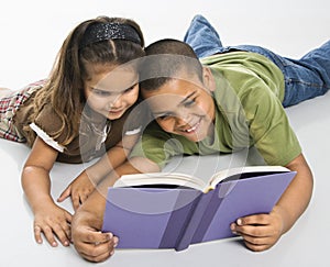 Brother and sister reading book together.