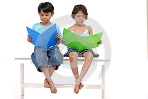 Brother and sister reading books on bench