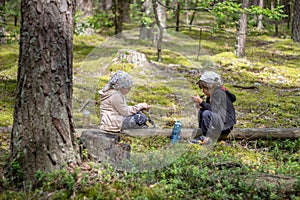 Brother and sister resting while hiking in the woods