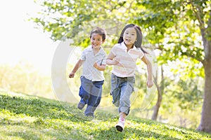 Brother and sister running outdoors smiling