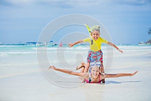 Brother and sister in scuba masks playing on the beach during the hot summer vacation day.