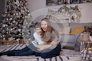 Brother and sister sitting on floor near christmas tree