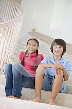 Brother And Sister Sitting On A Stairwell At Home