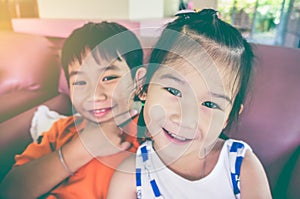 Brother and sister smiling and showing v-sign. Vintage tone.