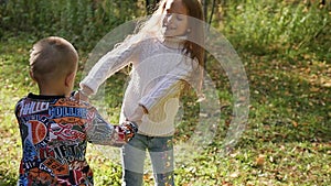 Brother and sister are spinning and having fun in the autumn park among the trees. Family concept