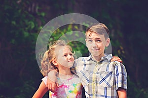 Brother and sister stand in an embrace in the park on the street and look at each other. The concept of happiness, family, love,