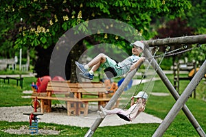 Brother with sister swinging in playground at Hallstatt, Austria