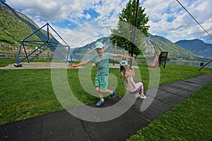 Brother with sister swinging in playground at Hallstatt, Austria