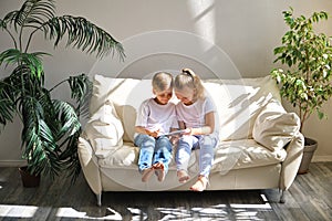 Brother and sister with tablet pc computer on the sofa in living room