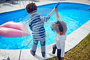 Brother and Sister Teamwork and Fun Cleaning the Pool with a Skimmer Net