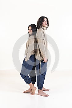 Brother and sister twins matching outfits while standing back to back. Studio shot. White background