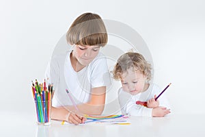 Brother and toddler sister paiting in white room