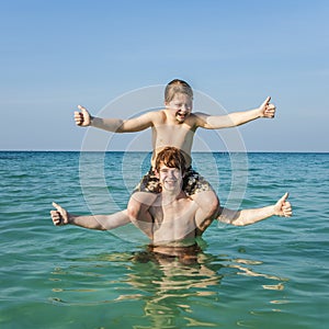 Brothers enjoying the clear warm water at the beautiful beach and playing pickaback