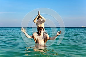 brothers are enjoying the clear warm water at the beautiful beach and playing pickaback