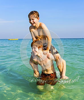 Brothers are enjoying the clear warm water in the ocean and play