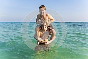 Brothers are enjoying the clear warm water in the ocean and play