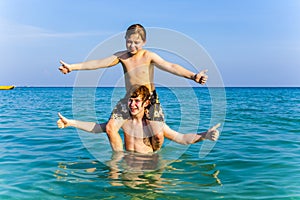 Brothers are enjoying the clear warm water in the ocean and play