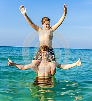 Brothers are enjoying the clear warm water in the ocean and play