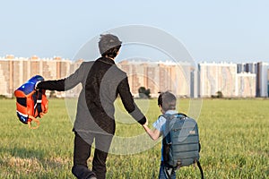 Brothers go to school. The teenager and his younger brother with backpacks hold hands, brothers smile happy faces of children.