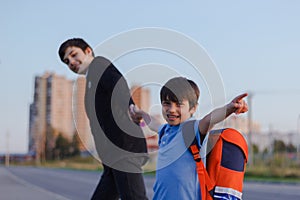 Brothers go to school. The teenager and his younger brother with backpacks hold hands, brothers smile happy faces of children.