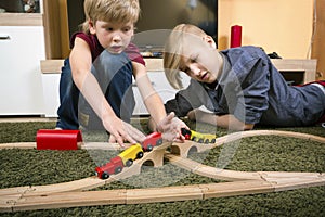 Brothers play with wooden train, build toy railroad at home or d