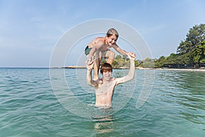 Brothers are playing together in a beautiful sea with crystal clear water