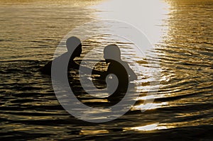 Brothers playing in the water of a lake at sunset