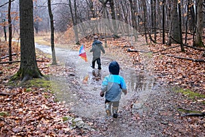 Brothers run through a forest trail in the rain