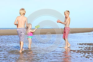 Brothers and sister playing on the beach