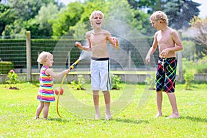 Brothers and sister playing with water hose in the garden