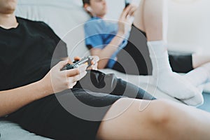 Brothers sitting on a sofa in living room and playing video games. Family relaxing time at home concept.