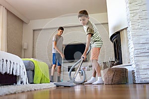 Brothers vacuuming floor at home