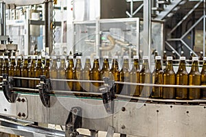 Brown 0.5-liter glass bottles of drinking water are on the conveyor in the production hall