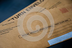 Brown absentee ballot return envelope with blank signature line on a desk with a pen