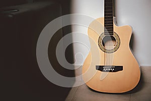 brown acoustic guitar on floor