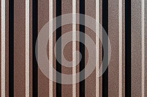 Brown aluminum fence brown. Background of striped fence chocolate color. Texture with vertical lines