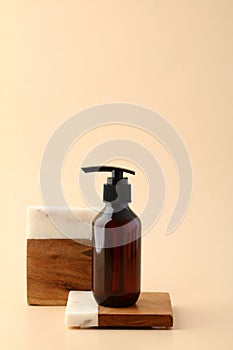 Brown amber glass bottle on podium on beige background. Natural body care cosmetic