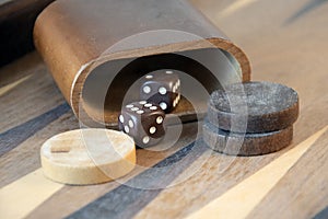 Brown backgammon dice and pieces on wooden game board