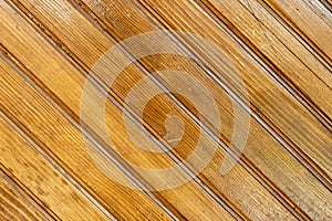 Brown background texture of a wooden fence made of diagonal planks of natural wood. Wooden background from wooden planks